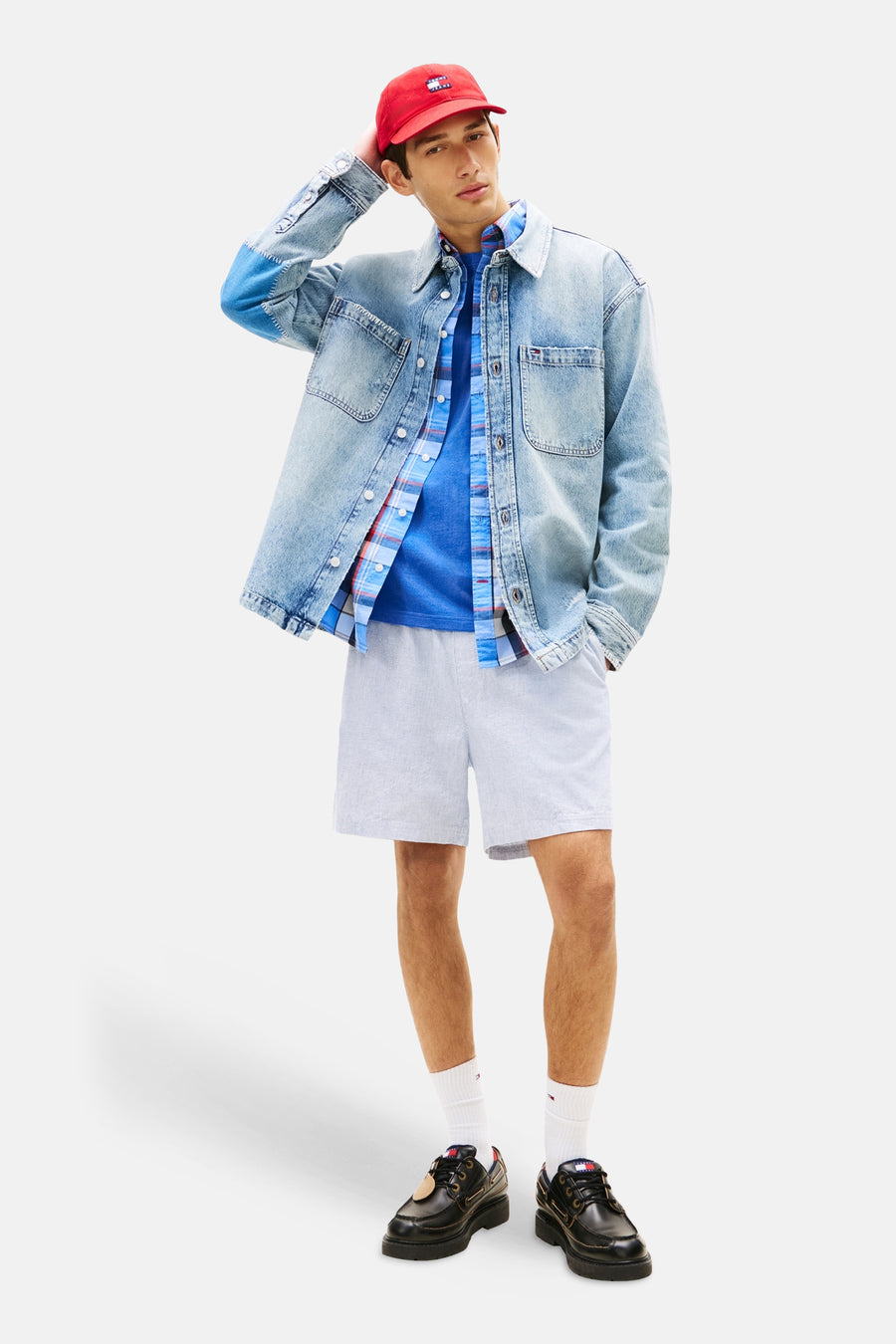 Short bleu de TOMMY JEANS, porté avec une chemise à carreaux, un t-shirt bleu et des chaussures bateau noires.