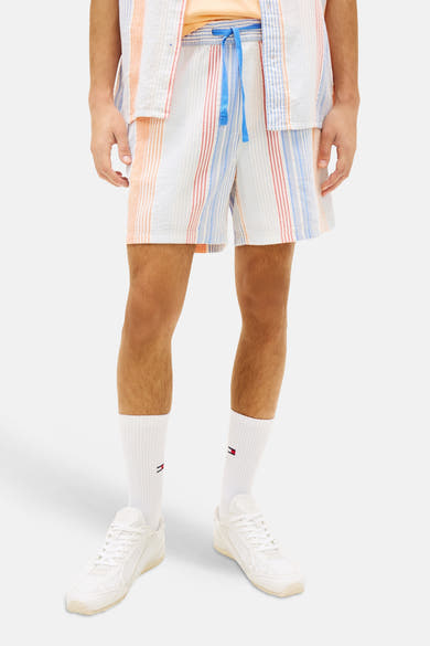 Short rayé orange par Tommy Jeans, avec cordon bleu, porté avec des chaussettes et des baskets blanches.