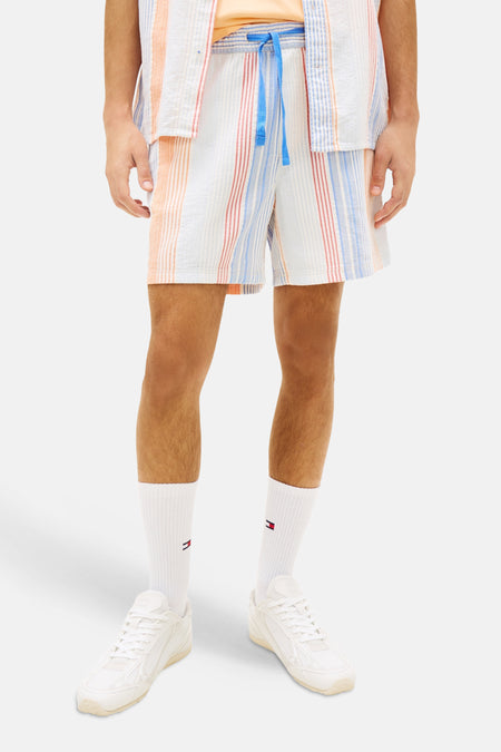 Korte oranje gestreepte broek van TOMMY JEANS met bijpassend gestreept overhemd, witte sokken en witte sneakers.