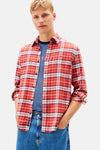 Rood geruit overhemd van TOMMY JEANS, gedragen over een gestreept T-shirt, met een wijde blauwe jeans.