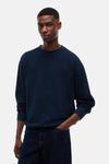 Navy blue ribbed crewneck sweatshirt with relaxed fit, worn by model in lifestyle front view, paired with dark denim jeans.