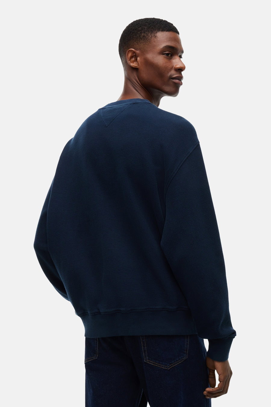 Navy blue waffle-knit crewneck sweatshirt with ribbed cuffs and hem, shown from back on model wearing dark jeans.