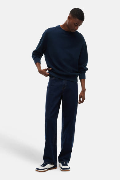 Navy blue ribbed crewneck sweatshirt with relaxed fit, worn with dark denim jeans and white sneakers, full-length lifestyle view
