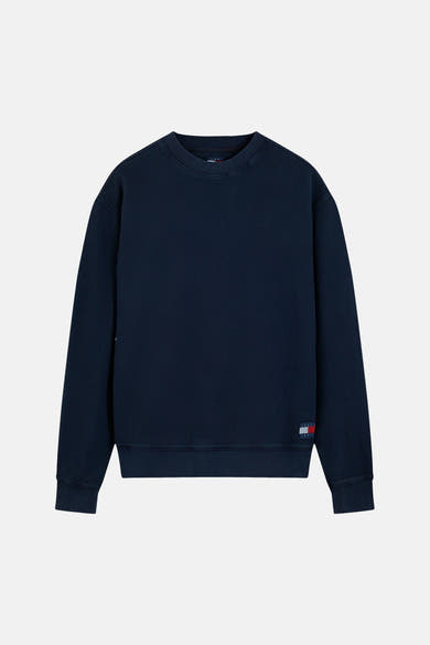 Navy blue waffle-textured crewneck sweatshirt by Tommy Jeans, featuring ribbed cuffs and hem, with small flag logo on left sleeve, front view.