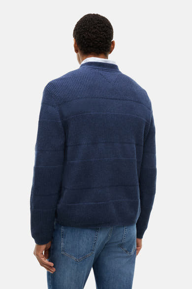 Blue ribbed knit crewneck sweater back view with horizontal textured panels, worn over white shirt with blue jeans