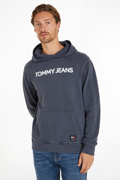 Blauwe hoodie van Tommy Jeans met de witte tekst "TOMMY JEANS" op de voorkant, gedragen met een blauwe jeans.
