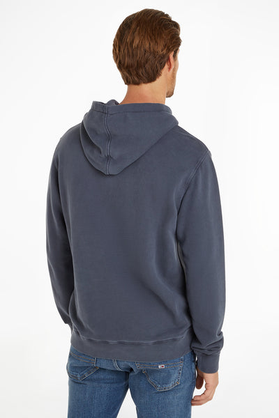 Blauwe hoodie van Tommy Jeans, met capuchon en van achteren zichtbaar gedragen met een spijkerbroek.
