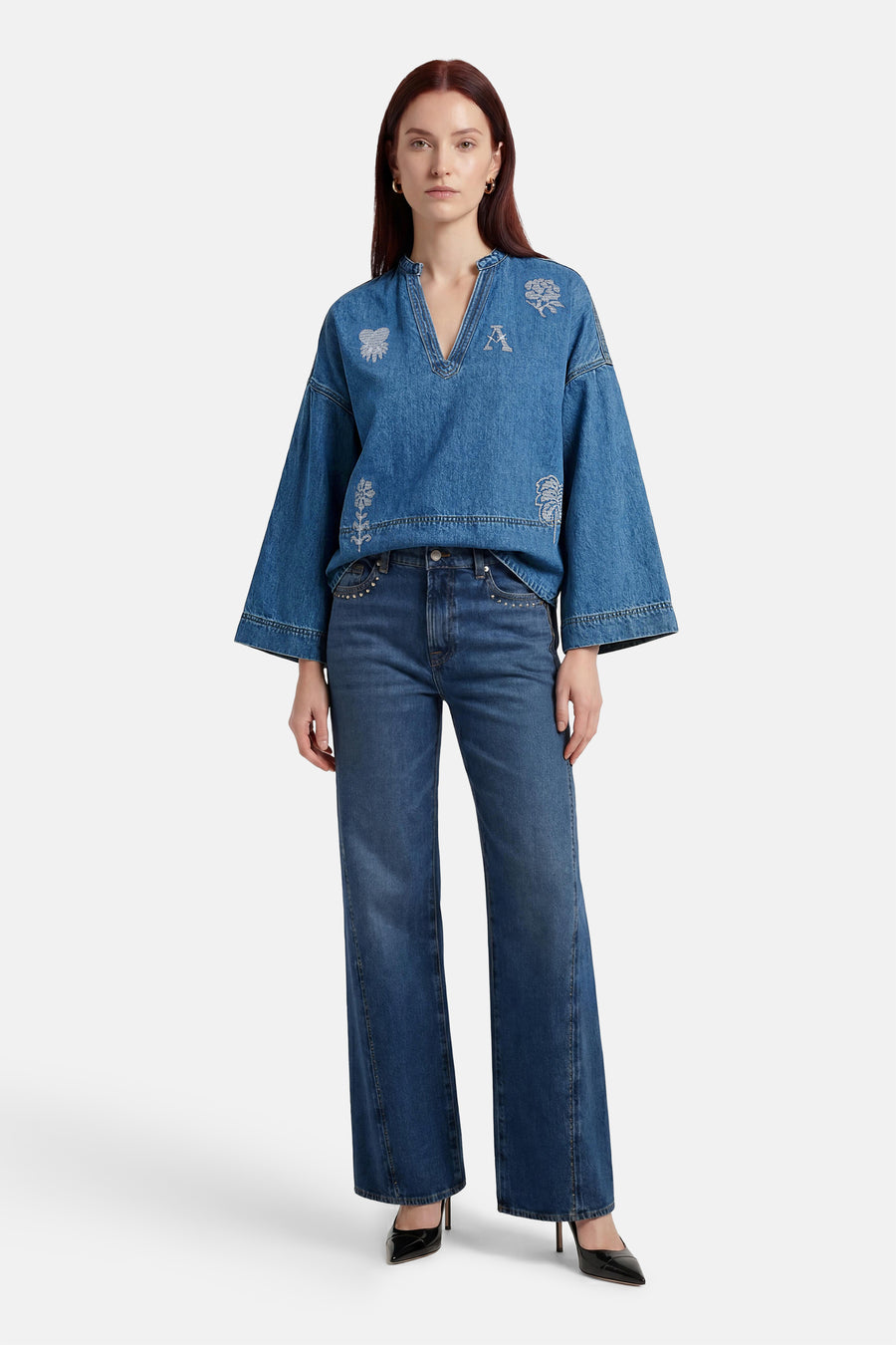 Blouse en denim bleu moyen d'ADORE, avec des broderies florales et des manches évasées, portée avec un jean et des escarpins noirs.
