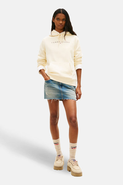 Sweat à capuche jaune clair de Tommy Jeans, porté avec une minijupe en jean et des chaussures plateforme.
