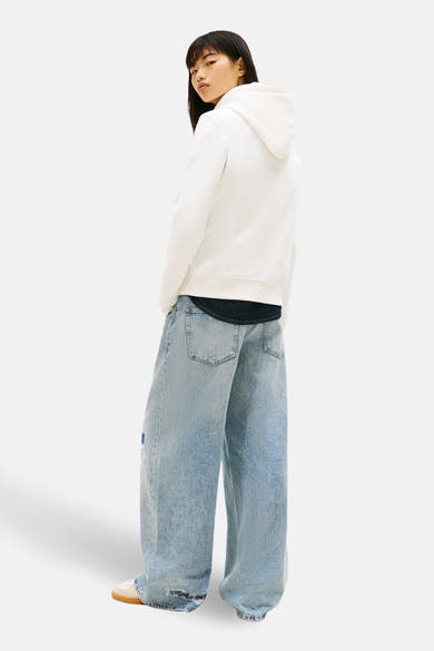 Witte hoodie van TOMMY JEANS, gedragen met een lichtblauwe wijde jeans.