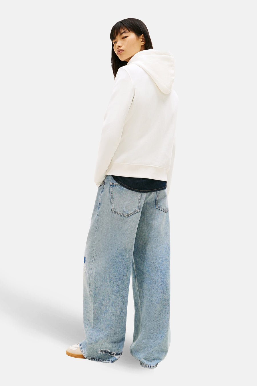 Witte hoodie van TOMMY JEANS, gedragen met een lichtblauwe wijde jeans.