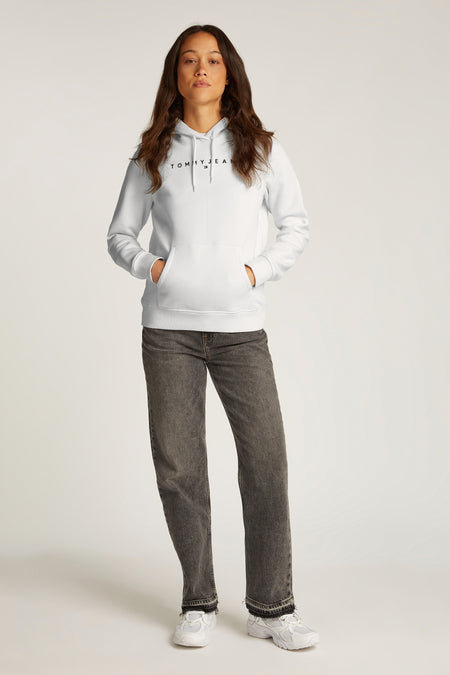 Witte hoodie van TOMMY JEANS, gedragen met een zwarte, uitgewassen spijkerbroek en witte sneakers.