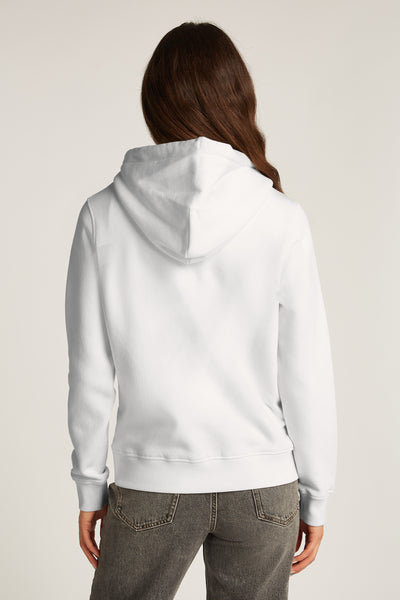 Sweat à capuche blanc de TOMMY JEANS, vu de dos, porté avec un jean gris.