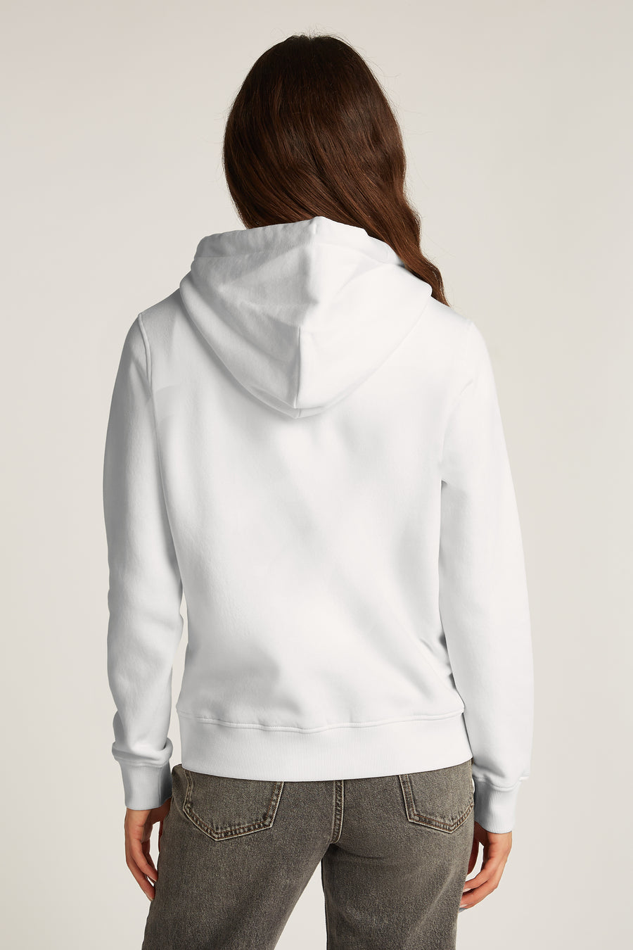 Witte TOMMY JEANS hoodie, van achteren gezien, gedragen met een grijze jeans.