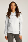 Witte hoodie van TOMMY JEANS, gedragen over een spijkerblouse, met een lichtblauwe jeans.