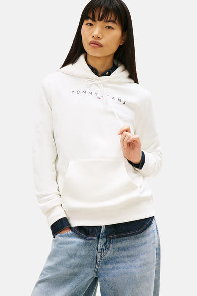 Sweat à capuche blanc de TOMMY JEANS, porté sur une chemise en jean, avec un jean bleu clair.