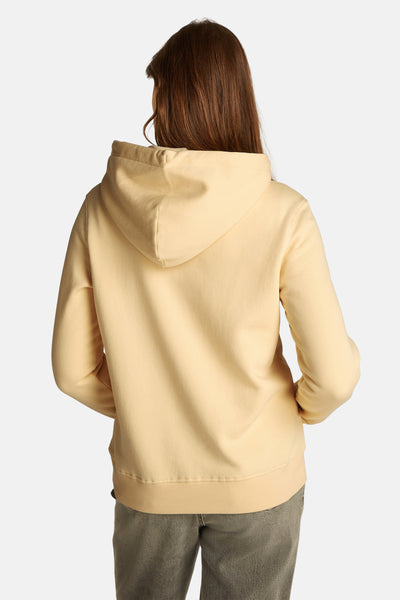 Sweat à capuche jaune de TOMMY JEANS, avec capuche et ourlet côtelé, porté avec un pantalon gris.