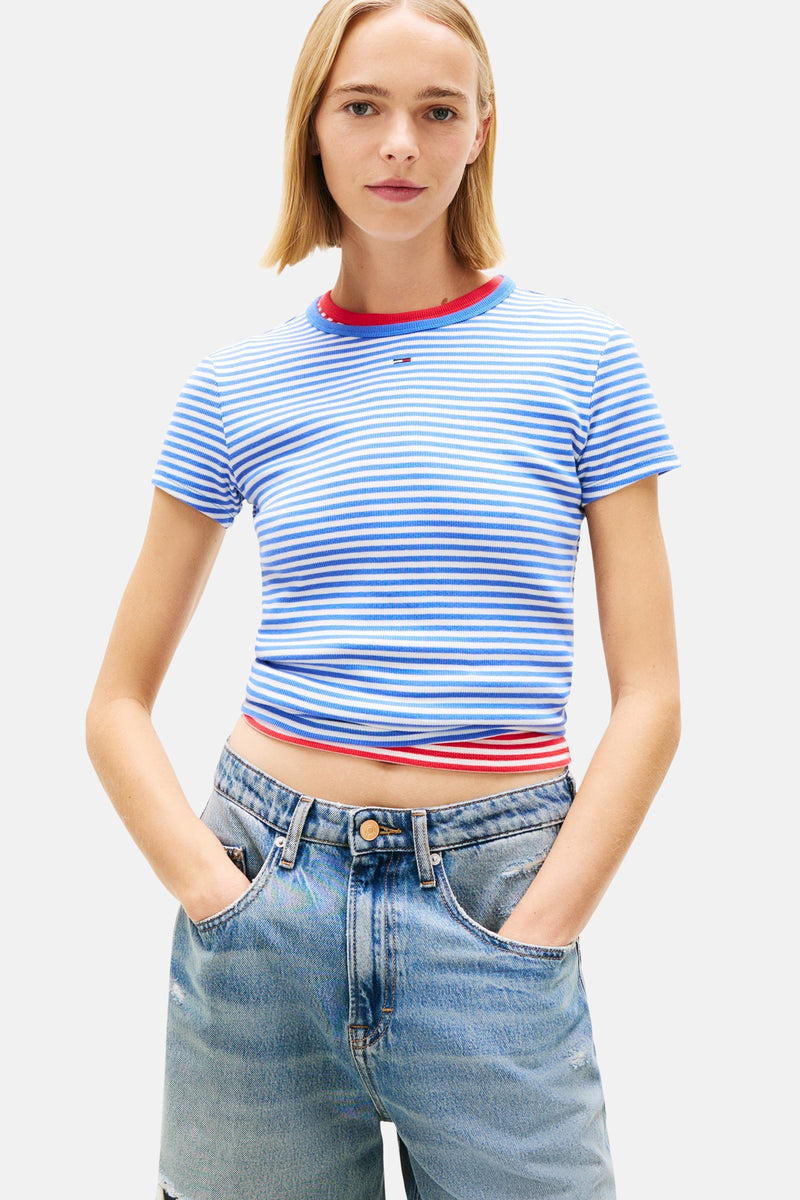 T-shirt bleu rayé by Tommy Jeans avec col et bas rouge, porté avec un jean taille haute.
