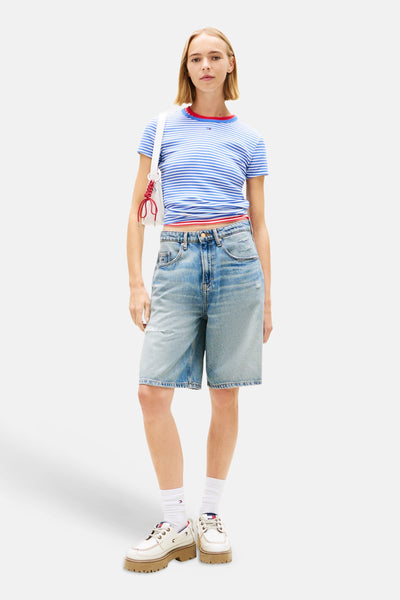 T-shirt bleu à rayures, de TOMMY JEANS, porté avec un short en jean ample et des chaussures à plateforme.