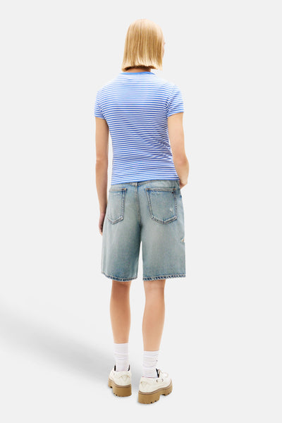 T-shirt rayé bleu et blanc de Tommy Jeans, porté avec un short en jean et des chaussures plateforme.
