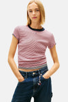 T-shirt à manches courtes multicolore de Tommy Jeans, rayures horizontales rouges et bleues, porté avec un jean bleu et un porte-clés décoratif.
