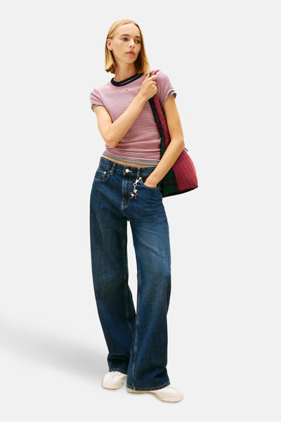 Multikleuren gestreept T-shirt van TOMMY JEANS, gedragen met een wijde jeans en een geruite tas.