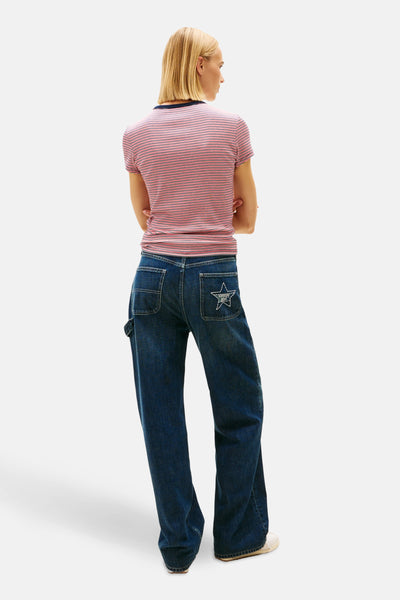 T-shirt à manches courtes multicolore de Tommy Jeans, rayures horizontales, porté avec un jean ample bleu foncé.