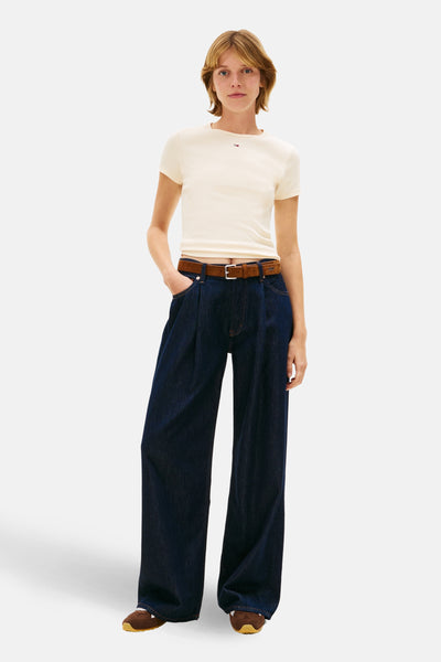 T-shirt uni à manches courtes jaune, de Tommy Jeans, porté avec un pantalon ample en denim foncé et une ceinture marron.
