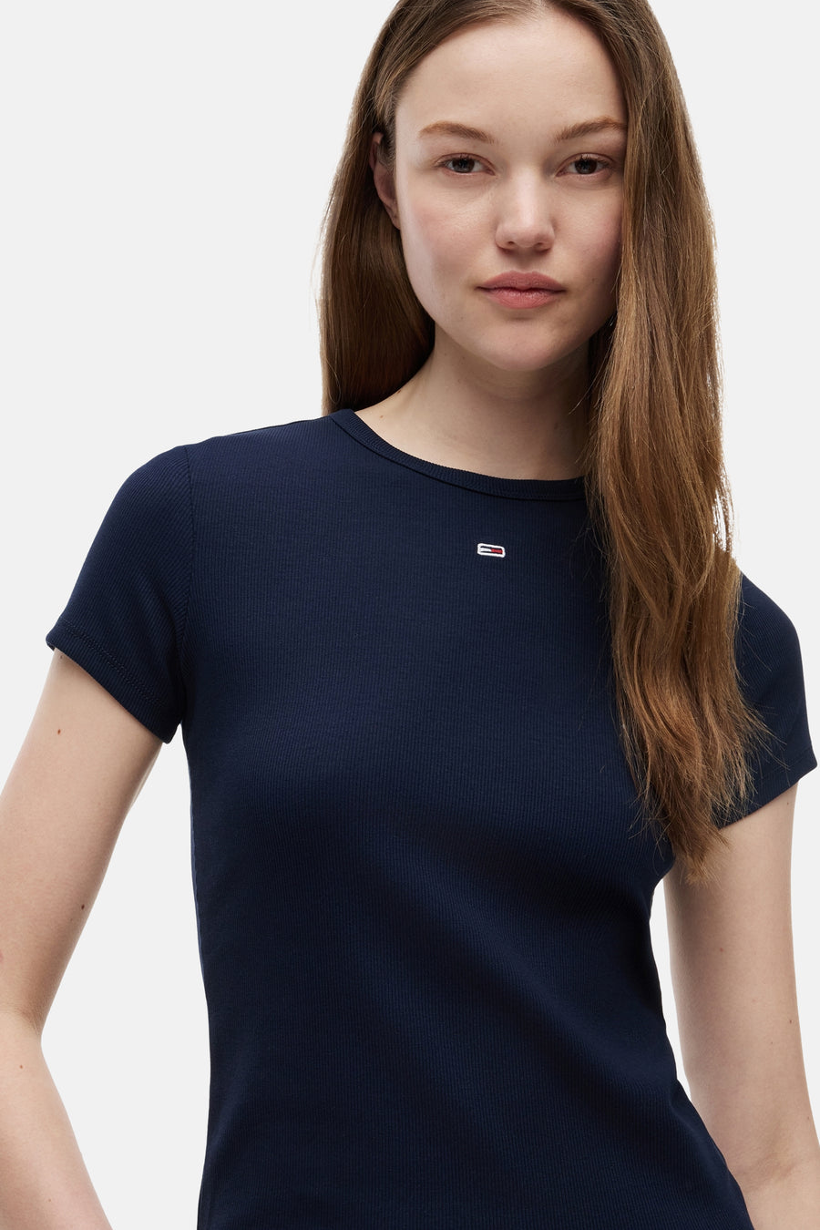 Top côtelé bleu marine à manches courtes de TOMMY JEANS avec un petit logo sur la poitrine, porté par une femme.