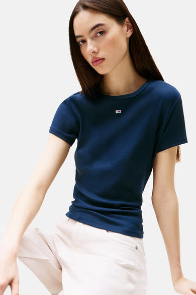 Top côtelé bleu à manches courtes de TOMMY JEANS avec petit logo poitrine, porté avec un pantalon clair.