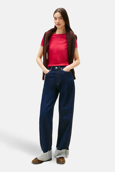 T-shirt rose à manches courtes de TOMMY JEANS, porté avec un cardigan marron et un jean ample.
