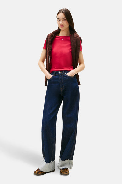 T-shirt rose à manches courtes de TOMMY JEANS, porté avec un cardigan marron et un jean ample.
