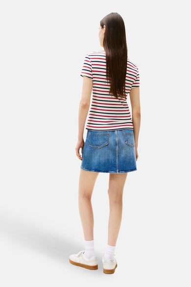 Multikleur gestreept T-shirt van TOMMY JEANS, gedragen met een blauwe spijkerrok en witte sneakers.