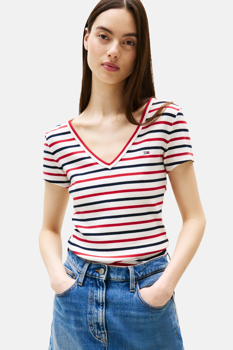 Geribde gestreepte T-shirt van TOMMY JEANS, met rood, wit en marineblauwe strepen, gedragen met een high-waisted spijkerbroek.