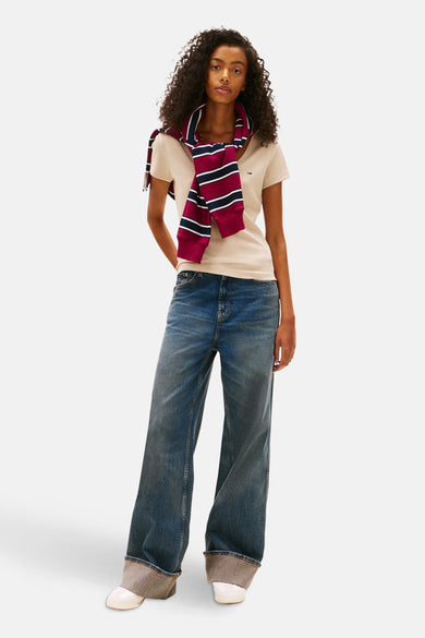 T-shirt beige à manches courtes de TOMMY JEANS, porté avec un pull rayé et un jean large à ourlet retroussé.
