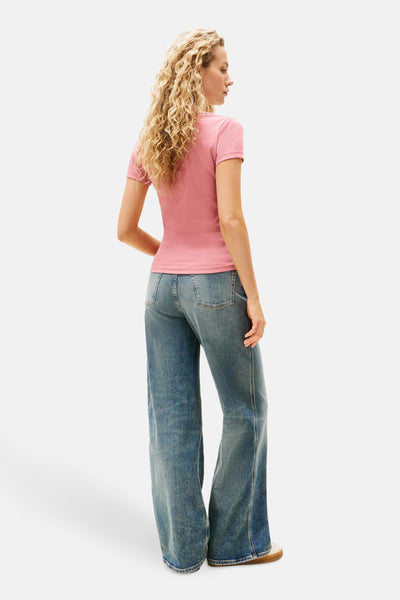 Roze T-shirt met korte mouwen van TOMMY JEANS, gedragen met een wijde blauwe jeans.