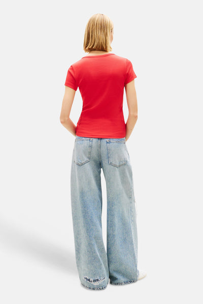 T-shirt rouge uni à manches courtes de TOMMY JEANS, porté avec un jean large et délavé.