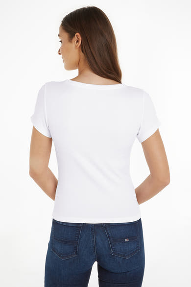 Top uni manches courtes blanc de Tommy Jeans, porté avec un jean bleu foncé.