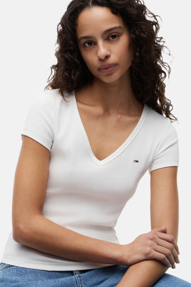 Top blanc uni à manches courtes de TOMMY JEANS, col en V côtelé et petit logo sur la poitrine.
