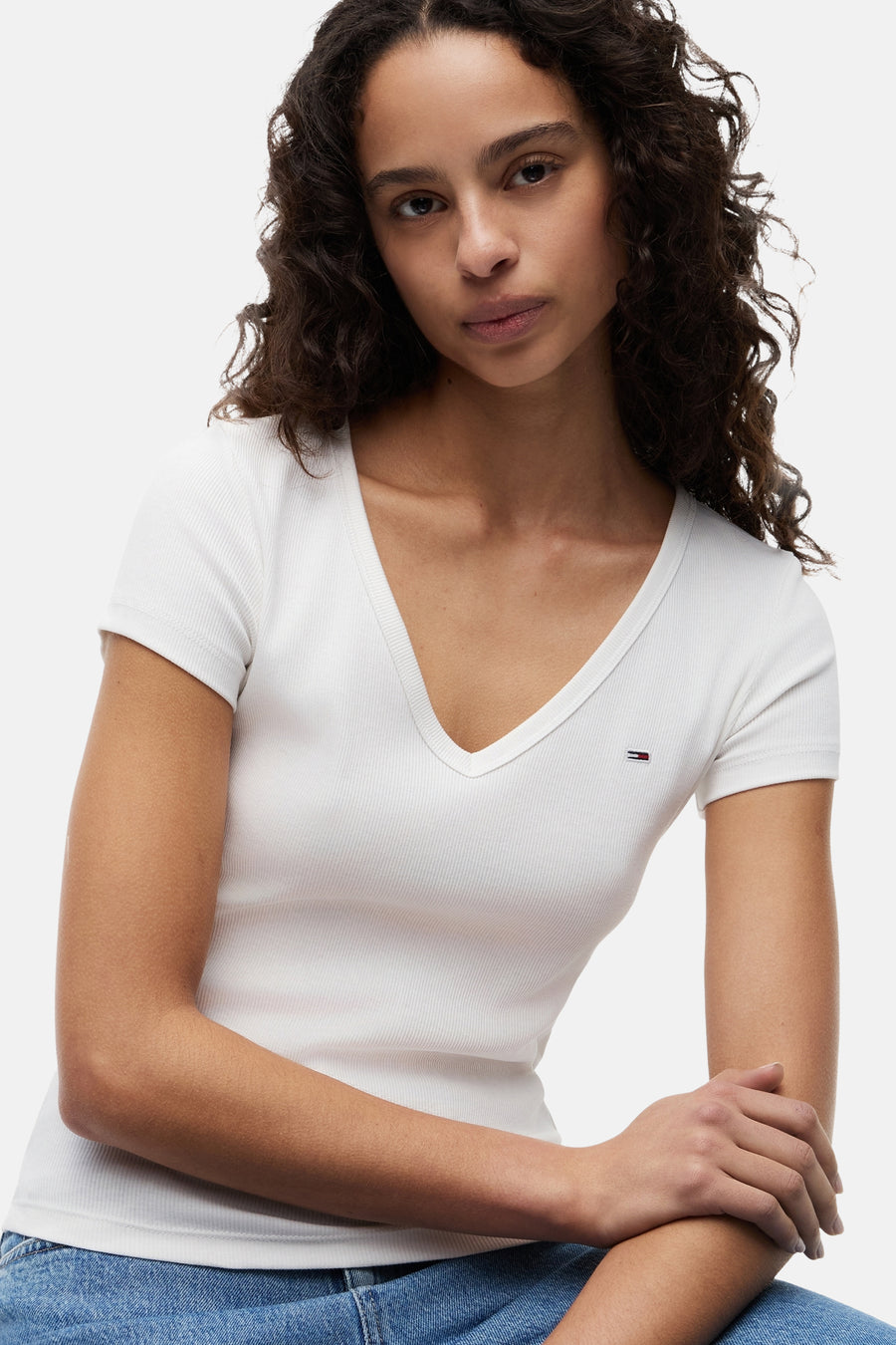 Top blanc uni à manches courtes de TOMMY JEANS, col en V côtelé et petit logo sur la poitrine.