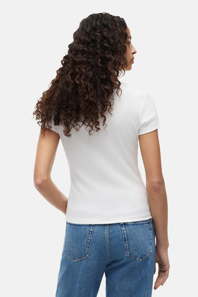 Top uni manches courtes blanc de TOMMY JEANS, côtelé, porté de dos avec un jean bleu.