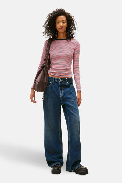 T-shirt à manches longues rayé multicolore de TOMMY JEANS porté avec un sac bandoulière et un jean bleu ample.
