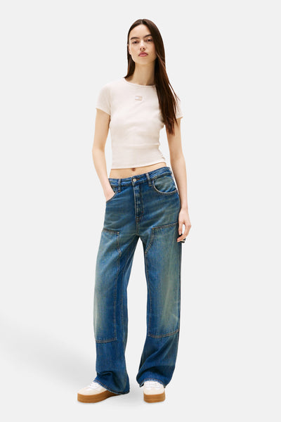 Beige T-shirt met korte mouwen van TOMMY JEANS, gedragen met een low-rise jeans.