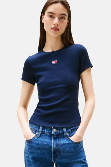 T-shirt bleu à manches courtes de TOMMY JEANS, en maille côtelée, porté avec un jean bleu taille haute.
