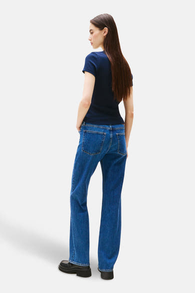 T-shirt bleu à manches courtes de TOMMY JEANS, porté avec un jean bleu et des chaussures noires, vue de dos.