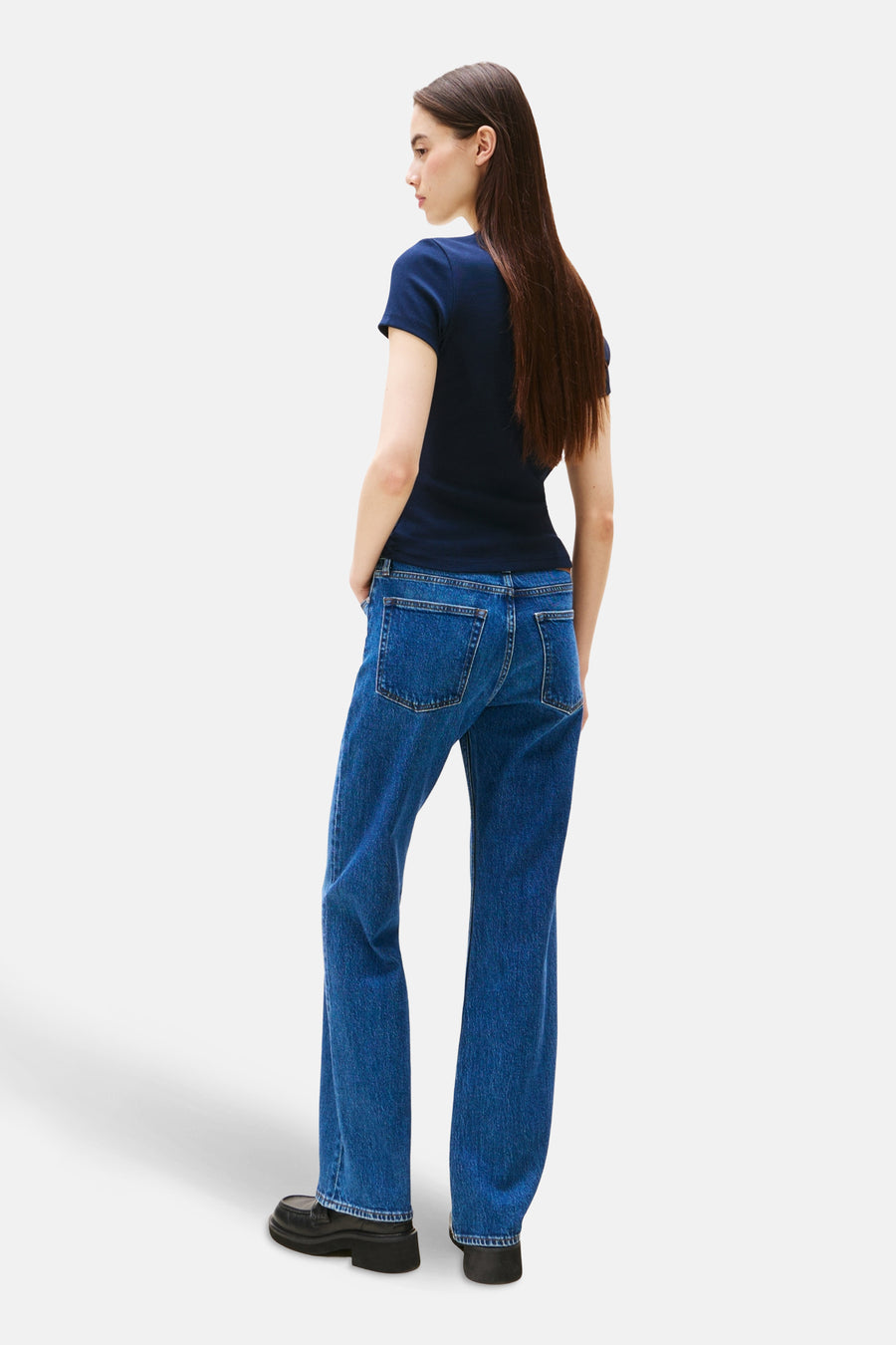 T-shirt bleu à manches courtes de TOMMY JEANS, porté avec un jean bleu et des chaussures noires, vue de dos.