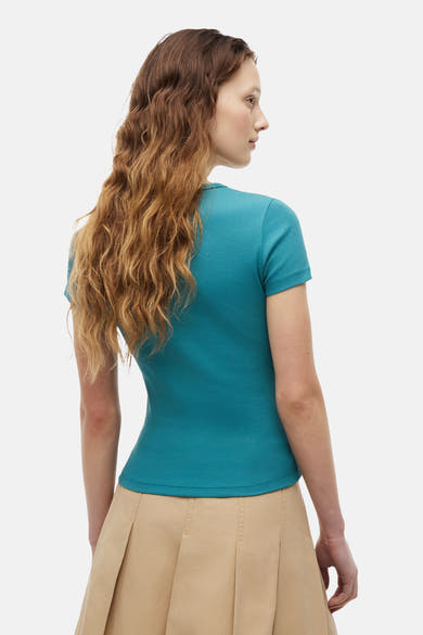 Geribd T-shirt met korte mouwen in het groen van TOMMY JEANS, achterkant, gedragen met een beige plooirok.