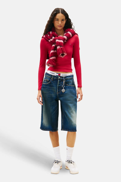 Roze T-shirt met lange mouwen van TOMMY JEANS, gedragen met een wijde spijkerbroek, witte sokken en een gestreepte sjaal.
