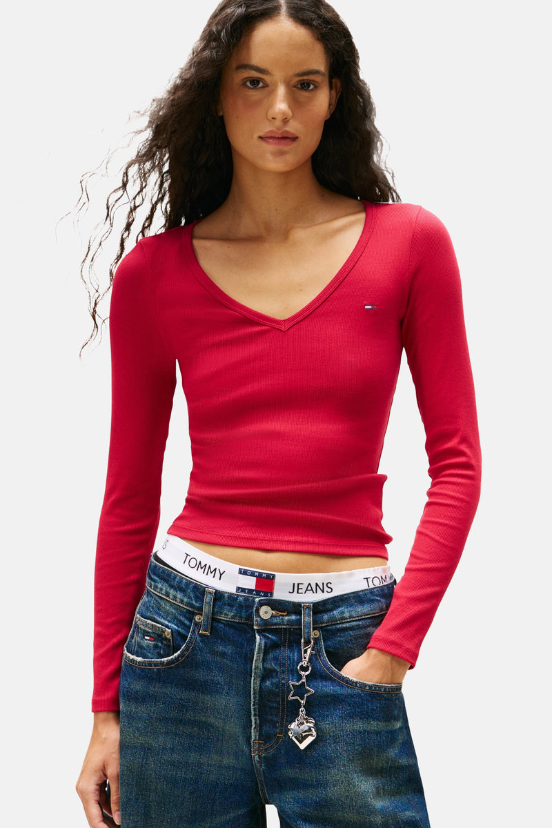 Roze T-shirt met lange mouwen van TOMMY JEANS, geribd met subtiel logo, gedragen met een low-rise jeans en een sleutelhanger.