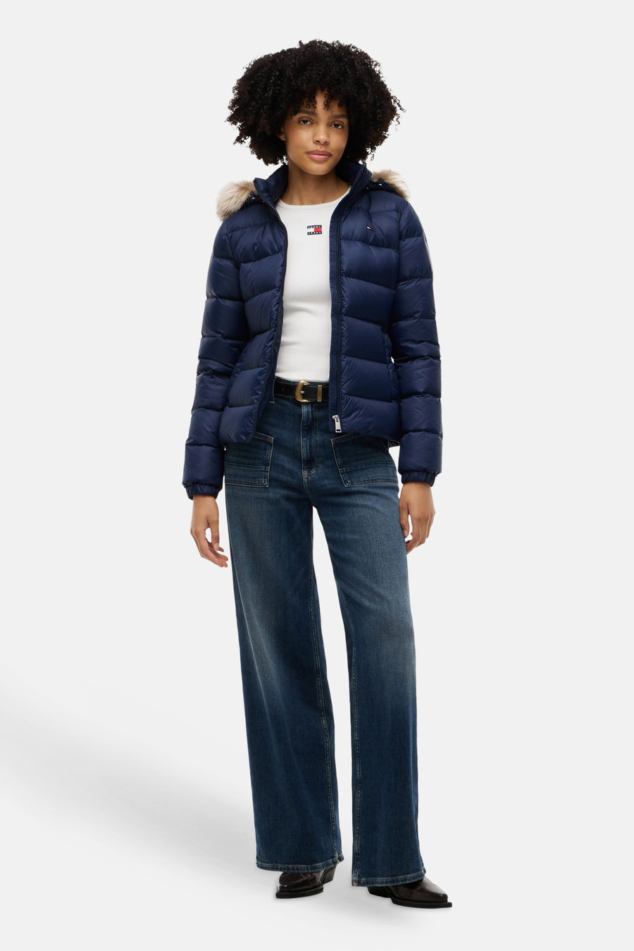 Navy blue quilted puffer jacket with fur-trimmed hood by Tommy Hilfiger, worn with white top and dark jeans, front view